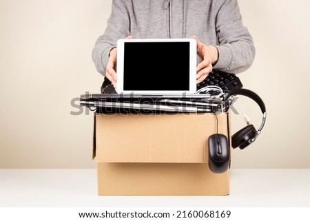 Woman hands holding digital tablet. Cardboard box full old used computers, phones, gadget devices for recycling. Planned obsolescence, e-waste, donation, electronic waste for reuse and recycle concept