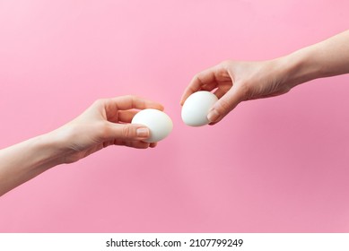 Woman hands holding Easter eggs for knocking on pink background. Easter celebration or creative concept. Adam creation