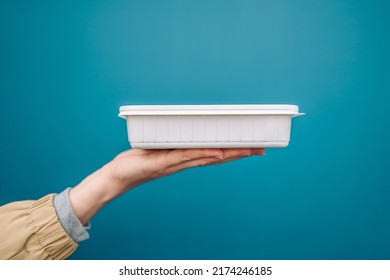 Woman Hands Holding Empty Plastic Disposable Food Container Mock Up With Copy Space On Blue Background. Delivery Food Concept. 