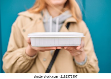 Woman Hands Holding Empty Plastic Disposable Food Container Mock Up With Copy Space On Blue Background. Delivery Food Concept. 