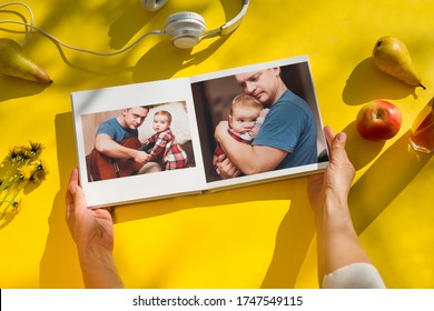 Woman Hands Holding A Family Photo Album Agains On A Yellow Background. Summertime. Flat Lay