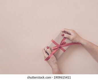 Händchen, die Geschenke mit rotem Band auf rosafarbenem Hintergrund halten, Kopienraum. Flachlage, Hände und Geschenkbox, Draufsicht. Valentine oder Liebe, Frühlingsferien, Weihnachten und Geburtstag Konzept.