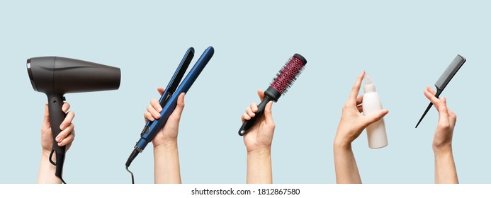 Woman hands holding hairdryer, straightener, hairbrush, tail comb and hair care essence in bottle isolated on blue background, horizontal banner format