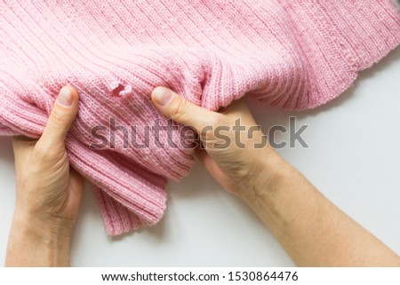 Woman hands holding the knitted thing with hole made by moth