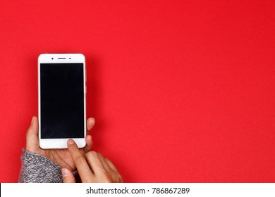 Woman Hands Holding Mobile Phone On Red Background With Copy Space. Flat Lay. Top View.