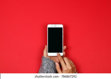 Woman Hands Holding Mobile Phone On Red Background With Copy Space. Flat Lay. Top View.