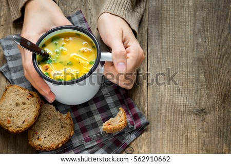 Woman hands holding mug of vegetable soup with parsley and croutons over wooden background - healthy winter vegetarian food