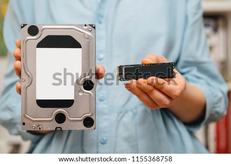 Woman hands holding new NVME PCIE SSD hard drive disk with high read and write speed with bigh old HDD drive