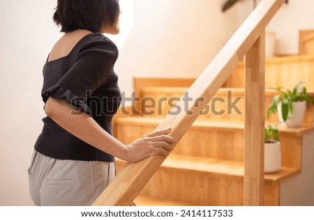 Woman hands holding on to the railing while walking up the stairs at home