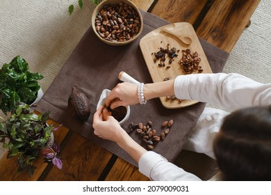 Woman hands holding organic cacao beans on wooden table, cocoa nibs, artisanal chocolate making in rustic boho style for ceremony. Degustation, Chocolate making with pounder close-up top view - Powered by Shutterstock