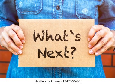 Woman hands holding piece of cardboard with words What`s Next against brick wall background. - Shutterstock ID 1742340653