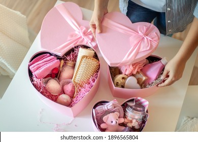 Woman hands holding pink colored heart shaped gift boxes of bath and body products for bridesmaids, bride and as a thoughtful gift for birthdays, anniversary, Valentine's Day, Mother's day, Christmas.