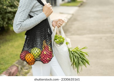 Woman hands holding shopping bag fruits and vegetables on the way home. Reusable cotton and mesh eco bags for shopping. Set zero waste plastic free concept. Sustainable lifestyle concept. - Powered by Shutterstock