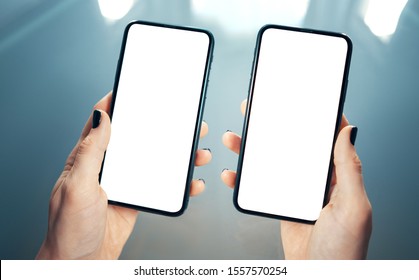 Woman Hands Holding Side By Side Two Smart Phones. Comparing, Analyzing Or Matching Two Products Or Services - Concept. Clean And Blurred Modern Background. Blank Screens With Copy Space - Image