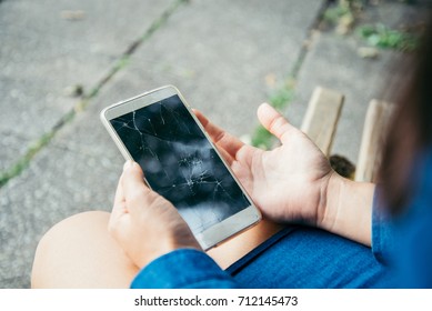 woman hands holding smartphone with cracked screen