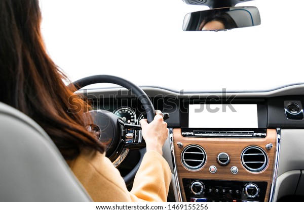 Woman hands holding steering wheel of a modern\
car. Hands on steering wheel of a car driving. Girl driving a\
vehicle inside cabin. Monitor in car with isolated screen. Car\
display with blank screen