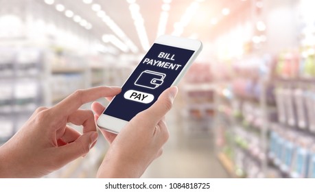 Woman hands holding and using smartphone with bill payment screen on blurred shopping mall interior background. Ecommerce concept.