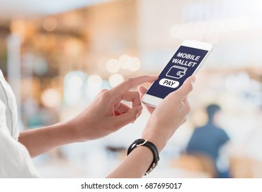 Woman Hands Holding And Using Smartphone With Bill Payment Screen, Wallet Icon And Pay Button On Blurred Restaurant Interior Background. Mobile Payment Concept.