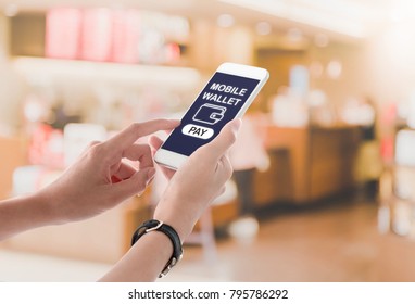 Woman Hands Holding And Using Smartphone With Mobile Wallet Screen, Wallet Icon And Pay Button On Blurred Restaurant Background. Mobile Payment Concept.