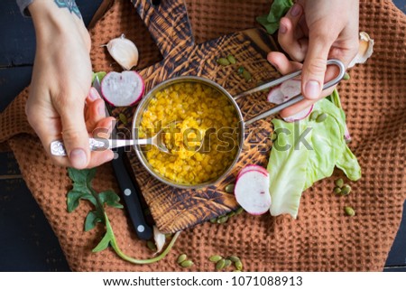 Woman hands holding veggie lentil peas Indian curry soup in metal saucepan with vegetables. Taste with spoon. Cooked for dinner or lunch. With organic raw vegetables. vegan vegetarian healthy food