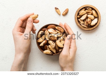 Woman hands holding a wooden bowl with brazil or bertholletia nuts. Healthy food and snack. Vegetarian snacks of different nuts.