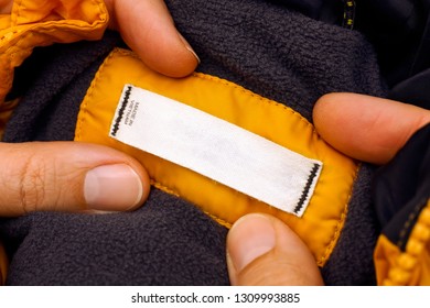 Woman Hands Holding Yellow Jacket With Clothes Label. Close-up.