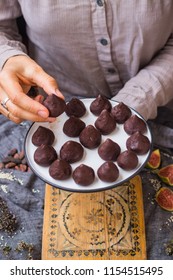 Woman hands holds chocolate truffle confectionary made with grated chocolate, cocoa or carob powder, coconut oil, chopped nuts, sweet nuts. Healthy vegan sweets or vegetarian sweets. - Shutterstock ID 1154515495