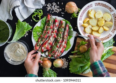 Woman hands holds plate with roasted baked eggplants slices with tomatoes, walnuts dressing, salad leaves and vegan sunflower seeds mayonnaise. Raw vegan vegetarian healthy food. Vegan lunch or dinner