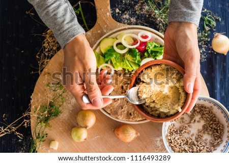 Woman hands holds and spreads dip sauce on garlic naan bread with butter, vegetables salad. Traditional Indian asian plain flatbread made with whole wheat flour. Raw vegan vegetarian healthy food