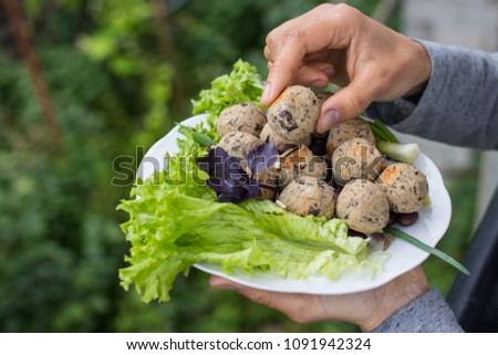 Woman hands holds vegan black beans falafel balls with salad leaves, basil, onion, tomato ketchup hot sauce served for lunch or dinner. Vegetarian healthy food