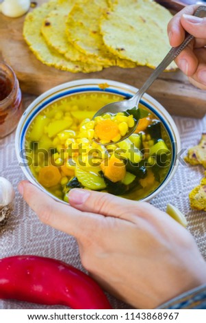 Woman hands holds vegetable corn soup with turmeric powder. Vegetarian lunch or vegan dinner with carrot and potato. Served with Indian traditional garlic naan flat bread or chapati (roti).
