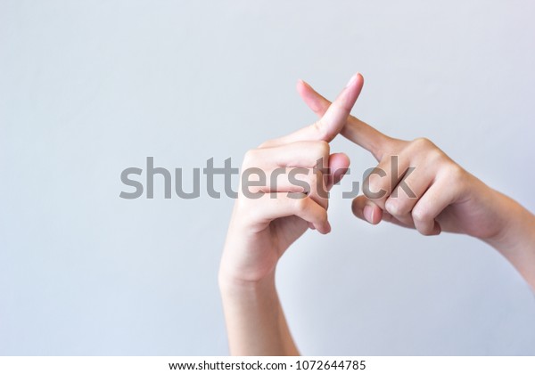 グレイの背景に交差する指を示す女性の手 間違ったジェスチャー の写真素材 今すぐ編集