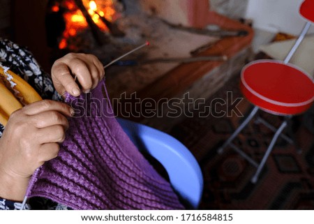 Woman hands knit.
woman knitting in front of the fireplace
