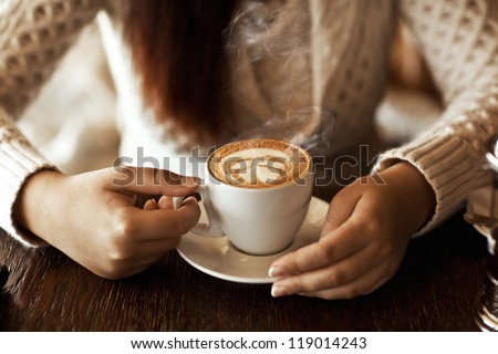 woman hands with latte on a wood table