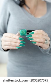 Woman hands and long nails   green manicure and bottles nail polish