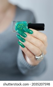 Woman hands and long nails   green manicure and bottles nail polish