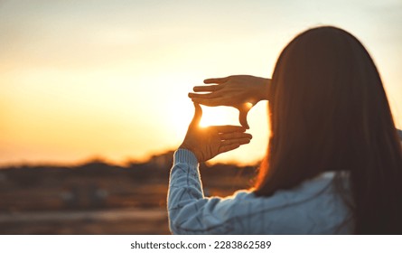 Woman hands making frame gesture with sunset, Female capturing the sunrise. Business planning, strategy and vision concept. - Powered by Shutterstock