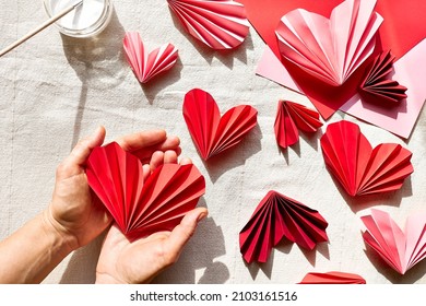 Woman hands making paper hearts. Origami garland. Symbol of love for valentines day, happy birthday, greetings, Mothers day, Women's day. Diy. Step by step.