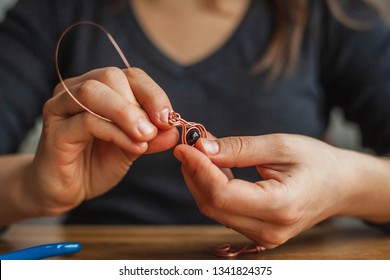 woman hands making wire wrapped jewelry preparation process wooden table. Female girl bends  crafts handmade copper  wire working tools on the table. Handmade bijouterie jewellery adornment. - Powered by Shutterstock