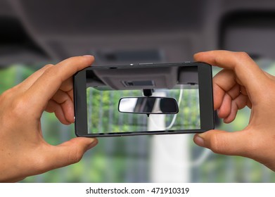 Woman hands with mobile cell phone to take a photo of car rearview mirror - Powered by Shutterstock