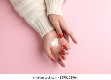 Woman hands, moisturizing cream for clean and soft skin in winter time, heart shape created from cream on pink background, space for text. Top view. Healthcare concept - Powered by Shutterstock