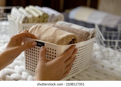 Woman Hands Neatly Folded Linens And Towels Use Marie Kondo Method With Sticky Label Tags Top View Closeup. Female Housewife Arms Sticking Names On Case Box For Comfortable Storage In Bedroom Closet