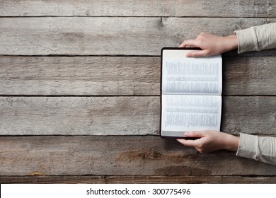 woman hands on bible. she is reading and praying over bible over wooden table - Powered by Shutterstock