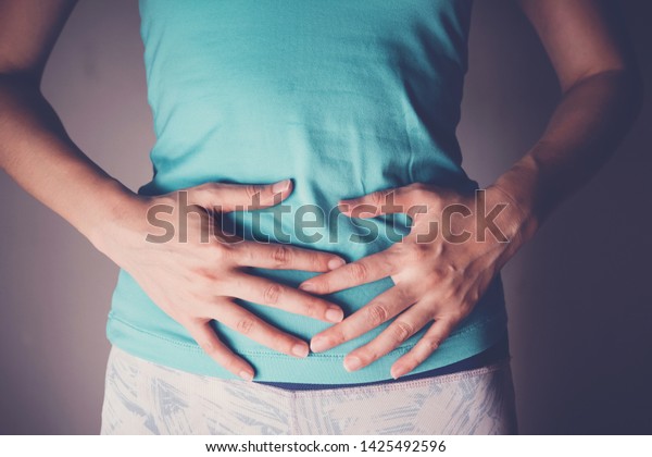 woman\
hands on her stomach, probiotics and prebiotics food for gut\
health, having stomachache, leaky gut, woman\
health