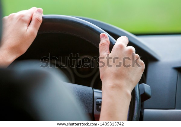 Woman hands on\
steering wheel driving a\
car.