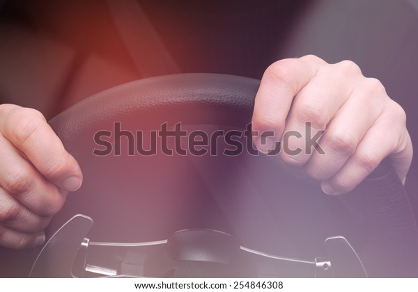 Woman hands on steering wheel of a car. Photo\
was taken through the\
windshield.
