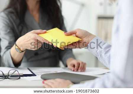 Woman hands over full envelope to her interlocutor. Salary in an envelope concept