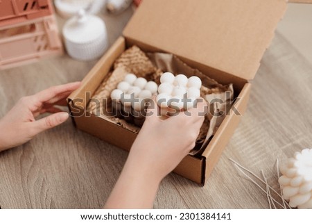Woman hands packing white candles in the box on the table
