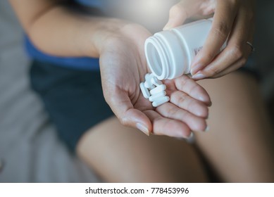 Woman hands with pill on spilling pills out of bottle,Women hand holding a white medicine