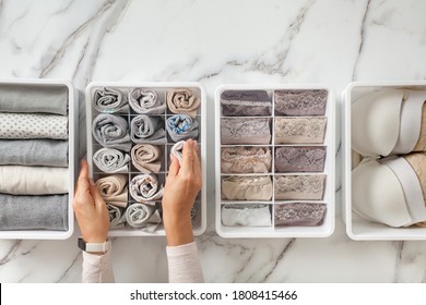 Woman hands placing wardrobe drawer organizers with full of folded underwears. Sock drawer with folded socks. Perfect and neatly setting of clothes. Linen drawer organization solution. Perfectionist.